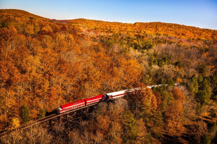 a long red train is on the side of a mountain