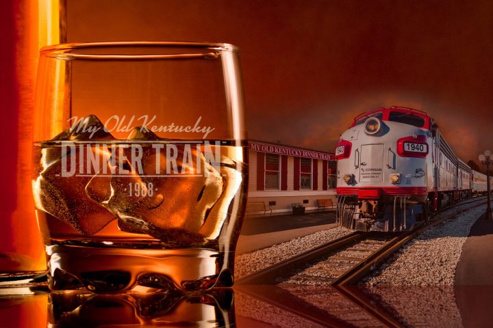 a glass of bourbon next to a train