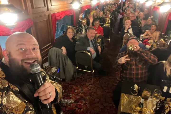a man with a microphone standing in front of a crowd on the dining car