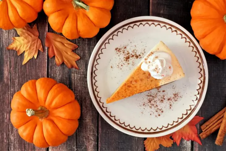 a slice of pie and pumpkins on top of a wooden table