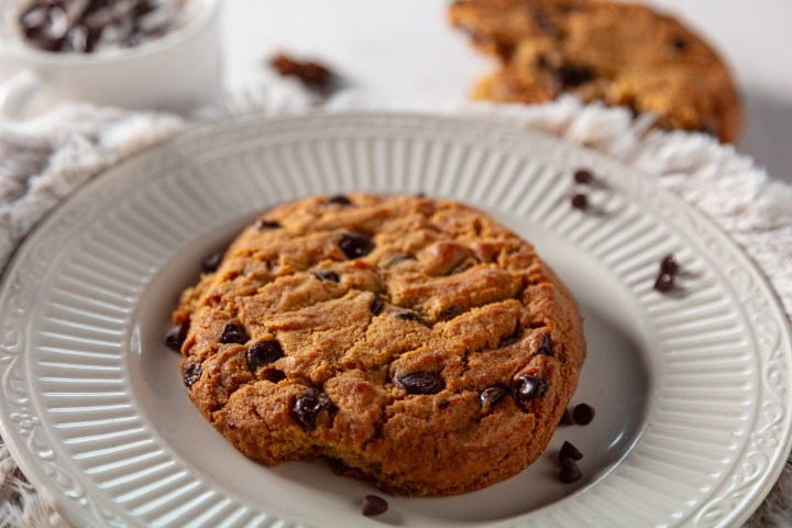 Chocolate chip cookie on a plate with a bite missing.