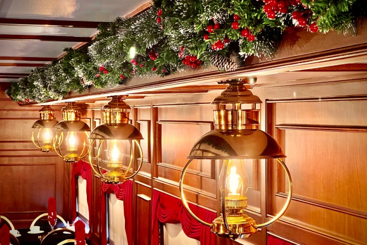 Festive train interior with garland and vintage lights.