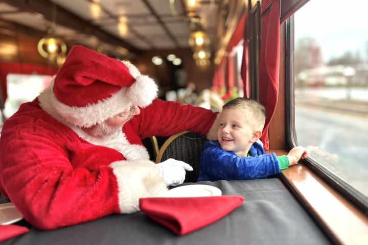 Santa chatting with a smiling child on a train.