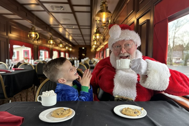 Child and Santa enjoying cookies and hot drinks on a train.