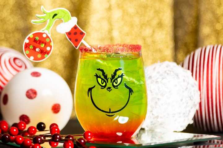 Festive green-red drink with Grinch face, holiday decor background.